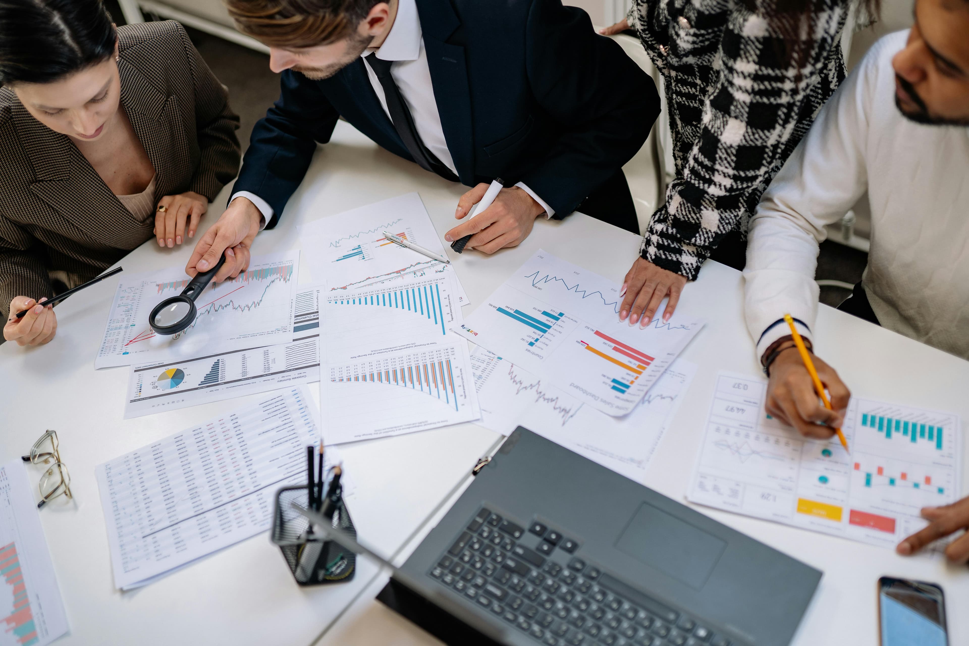 A group of diverse professionals analyzing charts and graphs on a table, discussing data trends and insights in a collaborative setting