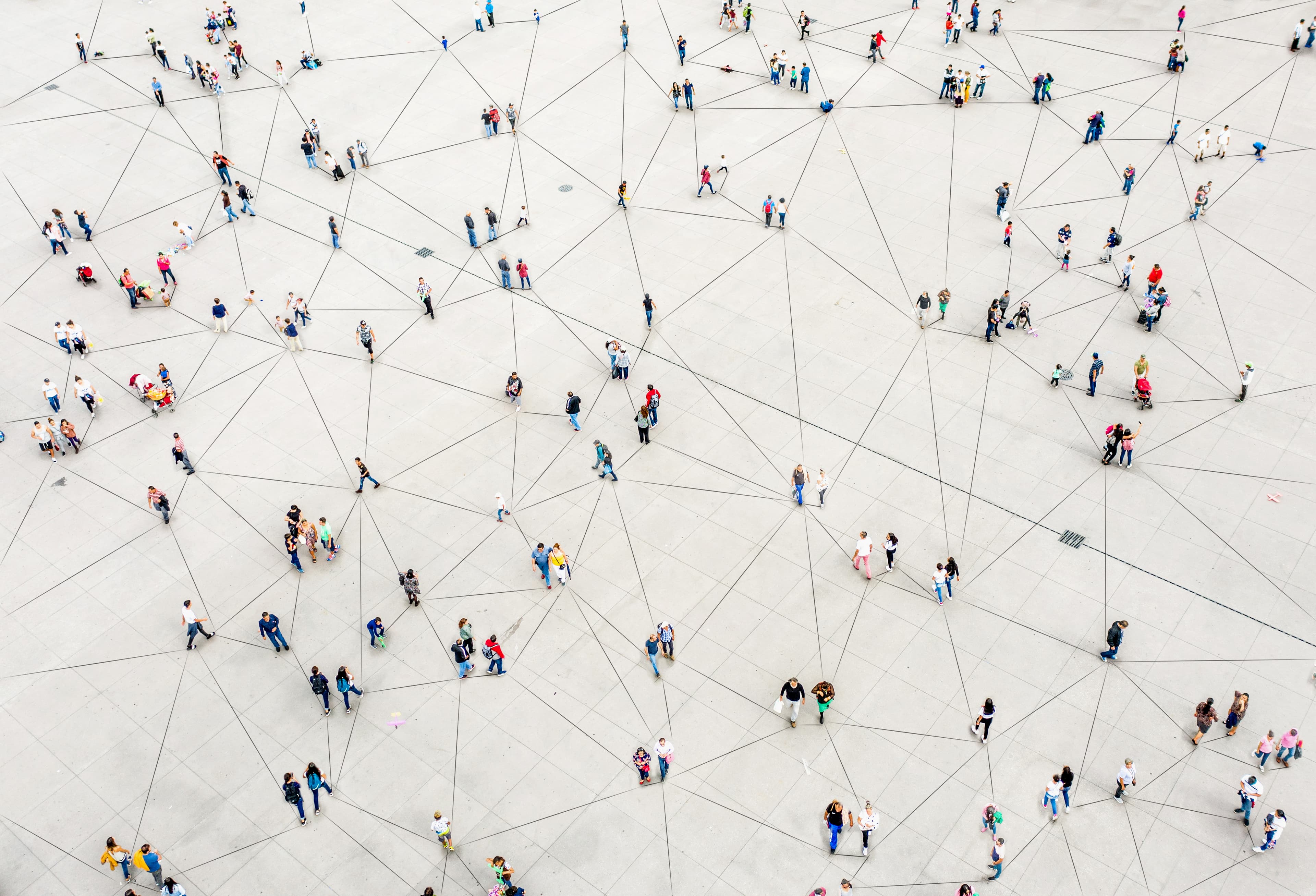 An aerial view of people scattered across a large open space with lines connecting them in a network-like pattern, symbolizing social connections